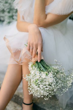 Gelinin elinde bir buket çigila. Beyaz monobouquet. Minimalizm tarzında düğün.