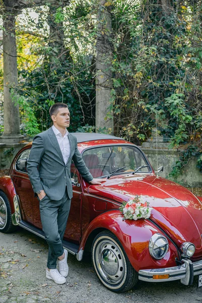 Atraktivní Evropan Svatebním Kostýmu Pózuje Pozadí Červeného Retro Auta — Stock fotografie
