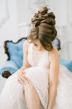 İnanılmaz ve duygusal gelin başını öne eğdi. Sabahları gelini bir araya getirmek ve saçında şık bir süsleme..