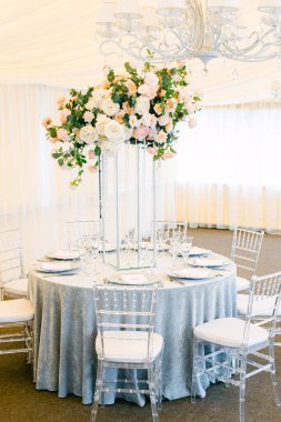 Lüks bir çadırda yemek servisi ve düğün yemeği için hazırlanan masayı hazırla. Güllerden ve kristallerden yapılmış masa süslemeleri.