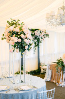 Masa hazır ve restorandaki gelin ve damat için güllerle süslenmiş. Taze çiçek ve masa örtülerinin bileşimi.