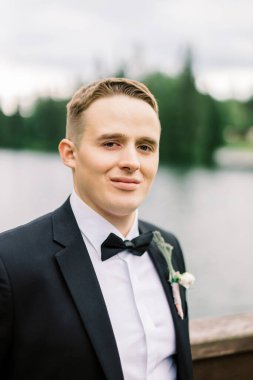 Düğün smokinli mutlu genç bir kocanın portresi. Klasik Avrupa açık hava düğünü kavramı