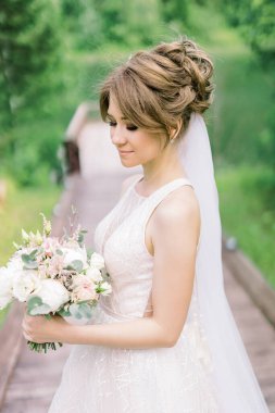 Pembe gelinlik içinde güzel bir gelin. Açık hava romantik portresi. Çiçekli, saç stili, balo elbisesi ve tül etekli, doğa tarafından poz veren çekici esmer kadın.