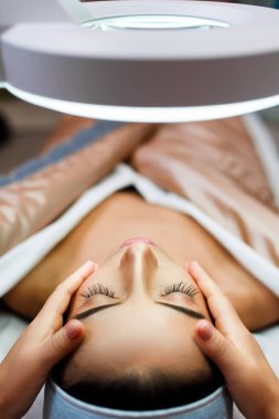 Üst tabaka genç bir kadın kafa masajı, terapi görüyor. Usta eller, müşterinin yoğurulan tapınaklarına masaj yapıyor. Esmer kız, kaplıca salonundaki kanepede yatıyor. Rahatlayın ve sağlık hizmeti kavramı