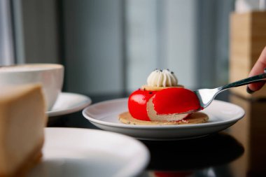 Kremalı ve kırmızı kremalı lezzetli bir kremalı pasta. Siyah bir masada beyaz bir tabakta servis yapmak. Kadınlar için tatlılar günü. Çatalla bir parça kes - tatlı yeme süreci.