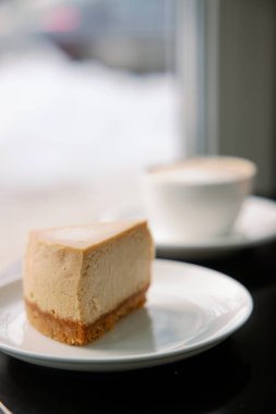 Klasik karamel rengi New York usulü peynirli kek ve masada kahve. Yan Görünüm