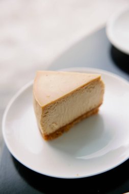 Beyaz tabakta klasik karamel renkli New York peynirli kek dilimi. Tatlı ve lezzetli tatlılar.