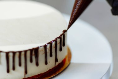 Yakın plan kadın pastayı çikolatayla süslüyor..