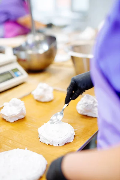 pastry chef spreads white meringue whipped cream on a special oven baking mat.