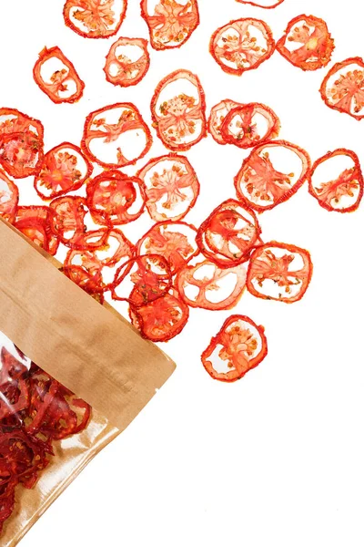由白色背景分离的有机红色西红柿制成的蔬菜片从可循环利用的纸包装中溢出 平面放置顶部视图 图库照片