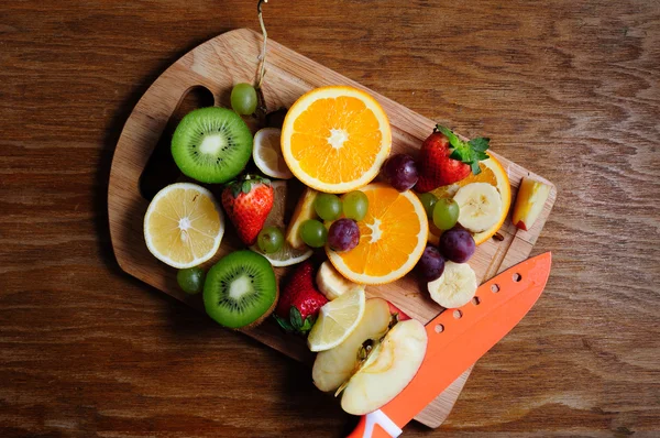 Juicy fruits with knife on a wooden board — Stock Photo, Image