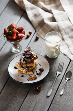 Ev yapımı Belçika waffle beyaz çikolata sosu, çilek, fındık, badem, pudra şekeri ve süt cam tabakta