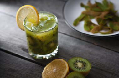 Taze kivi ve turuncu, ahşap masa üzerinde sağlıklı içecek.