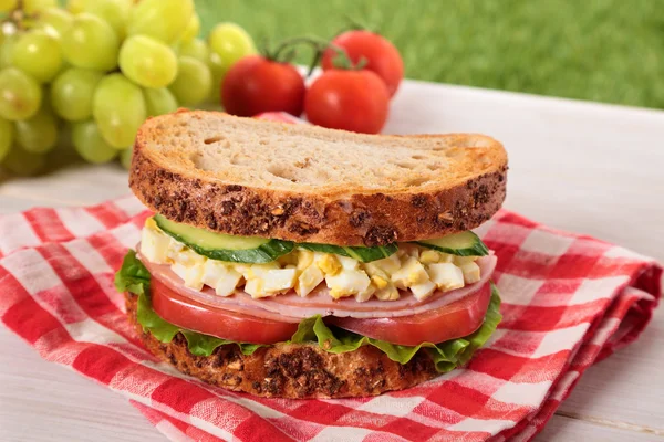 Ham and egg picnic sandwich on summer outdoor table — Stock Photo, Image