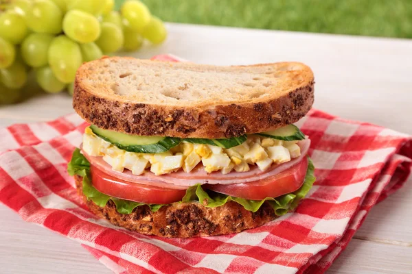 Ham and egg picnic sandwich on summer outdoor table — Stock Photo, Image