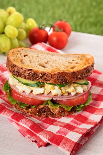 Ham and egg picnic sandwich on summer outdoor table — Stock Photo, Image