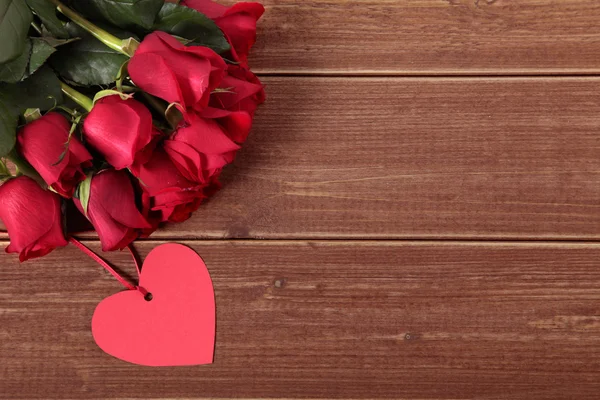 Valentinshintergrund aus Geschenkanhänger und roten Rosen auf Holz. Raum für — Stockfoto