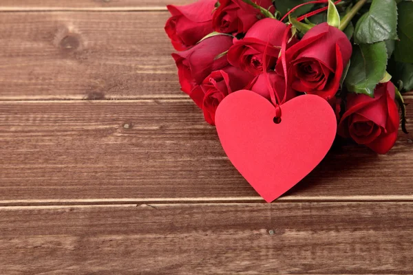 Valentinshintergrund aus Geschenkanhänger und roten Rosen auf Holz. Raum für — Stockfoto