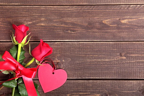 Valentinshintergrund aus Geschenkanhänger und roten Rosen auf Holz. Raum für — Stockfoto