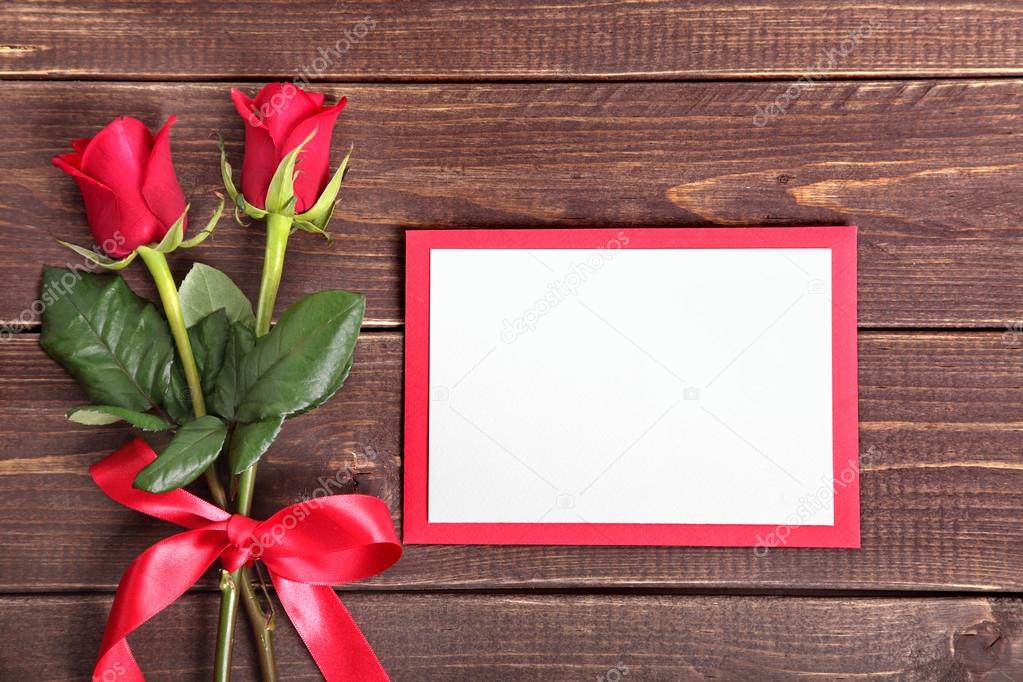 Valentine background of  red roses and card on wood. Space for c