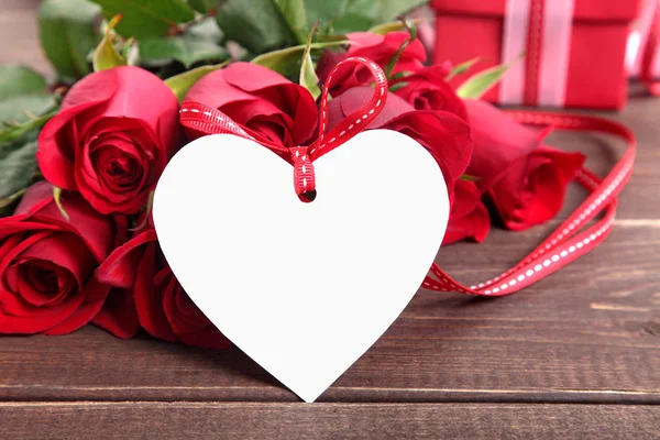 Valentinstag Hintergrund der weißen Geschenkanhänger und roten Rosen auf Holz. s — Stockfoto
