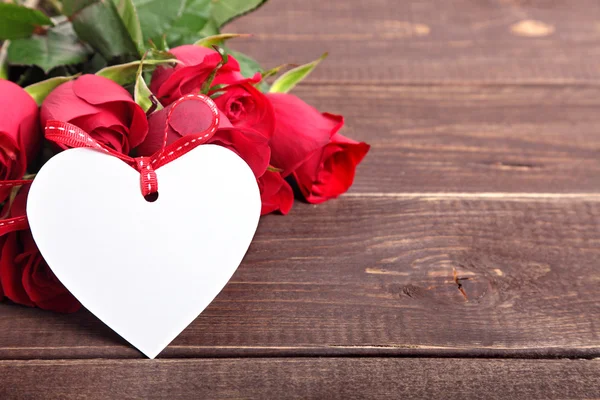 Valentine achtergrond van witte geschenk tag en rode rozen op hout. S — Stockfoto