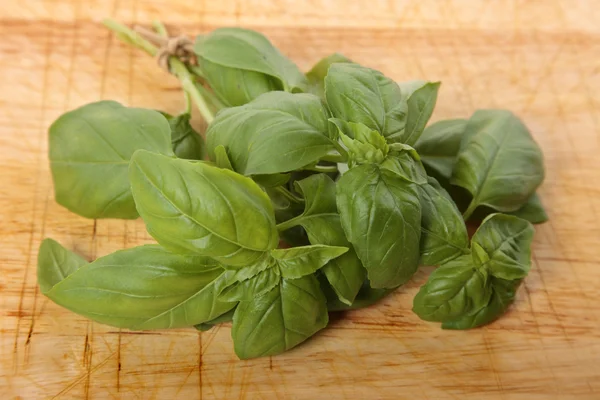 Bos verse basilicum op een oude houten snijplank — Stockfoto