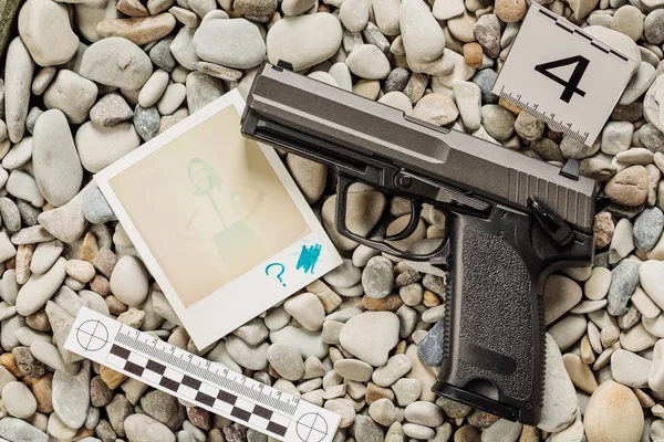 Investigación de la escena del crimen - recoger pistola en la playa — Foto de Stock