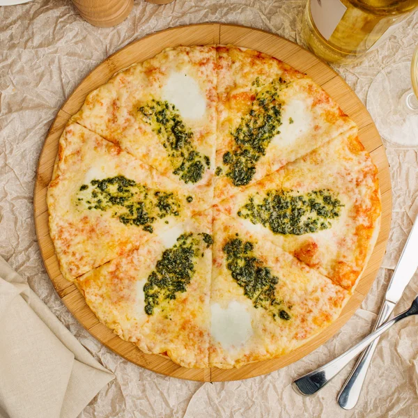 Foto de pizza crujiente en plato de madera, con botella de aceite de oliva — Foto de Stock