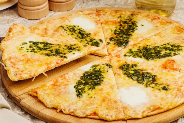 Foto de pizza crujiente en plato de madera, con botella de aceite de oliva — Foto de Stock