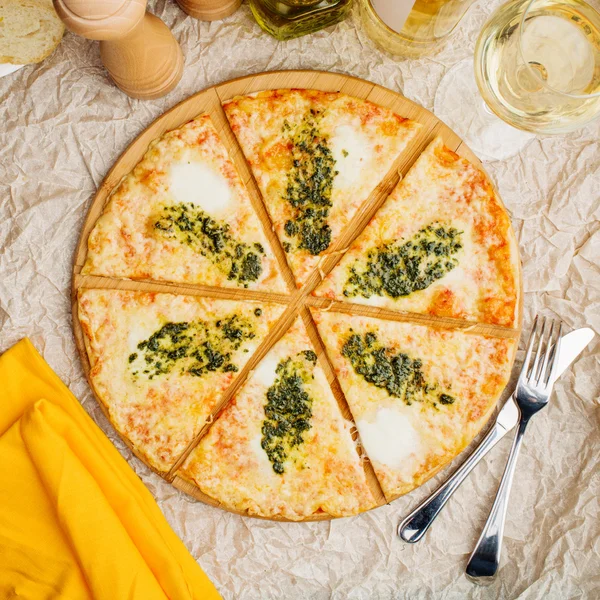 Foto de pizza crujiente en plato de madera, con botella de aceite de oliva — Foto de Stock