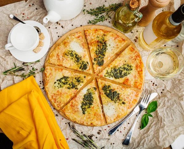 Foto de pizza crujiente en plato de madera, con botella de aceite de oliva — Foto de Stock