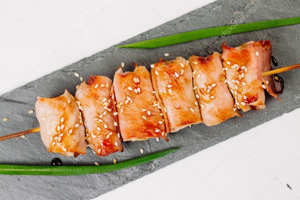 grill meat on a wooden skewer with green onions on a white background
