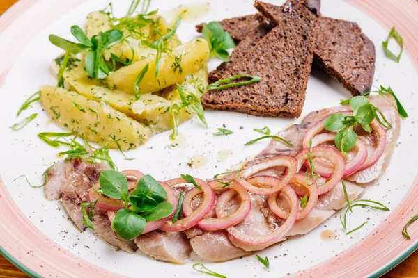 Le plat avec hareng, pommes de terre, oignons et bâtonnets de brie . — Photo