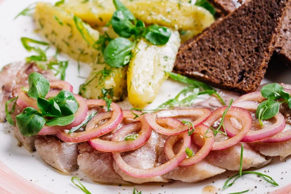 Блюдо с сельдью, картошкой, луком и сушеными палочками . — стоковое фото
