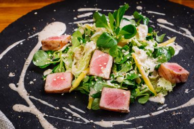 Kurutulmuş tuna susam plaka üzerinde yeşil salata ile kaplı