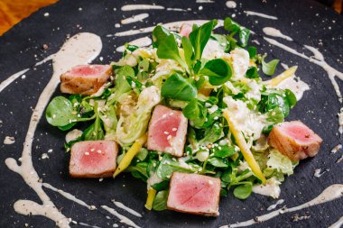 Kurutulmuş tuna susam plaka üzerinde yeşil salata ile kaplı