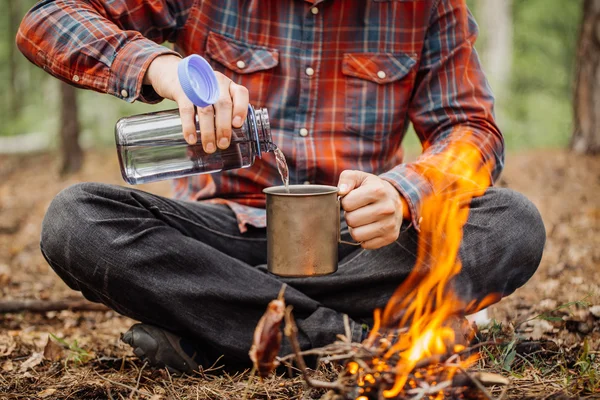 Man traveler pours water from a bottle into a metal mug. — Stock Photo, Image