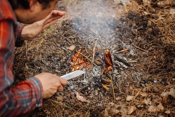 Человек путешественник разжигает костер в летнем лесу . — стоковое фото