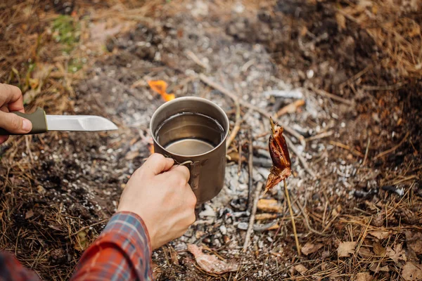 Mann hält Becher mit Wasser in der Nähe des Feuers im Freien — Stockfoto