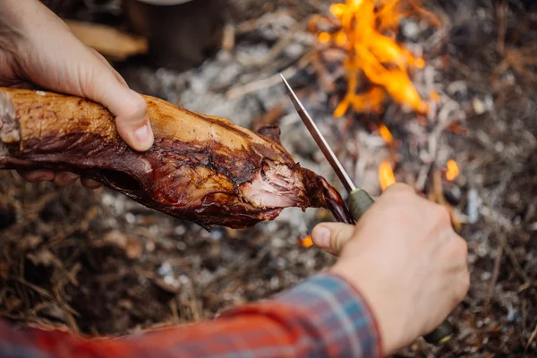 Hombre tallando carne de conejo a la parrilla en el campamento forestal. Vista superior . —  Fotos de Stock