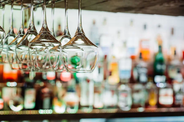 Copas de vino colgadas de vigas metálicas sobre fondo desenfocado . — Foto de Stock