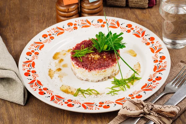 Русский салат из сельди на тарелке на деревянном столе — стоковое фото
