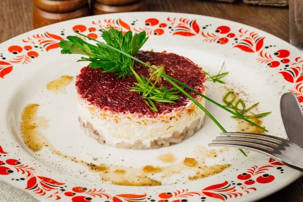 Русский салат из сельди на тарелке на деревянном столе — стоковое фото
