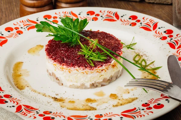 Ensalada de arenque ruso en plato sobre mesa de madera — Foto de Stock