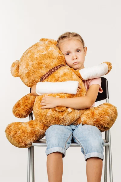 Törött karral unatkozó kislány átölelte a puha játék medve. — Stock Fotó