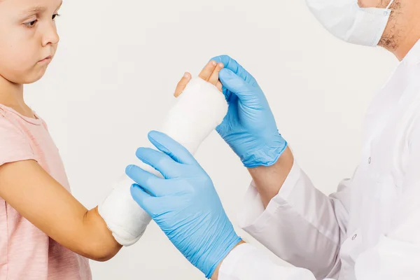 Kvinnliga läkare inspekterar bruten hand lilla patienten. — Stockfoto