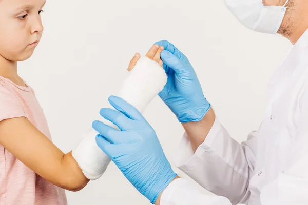 Female doctor inspecting broken hand of little patient. Royalty Free Stock Photos