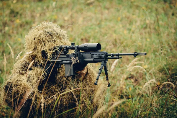 Снайпер в траве смотрит в прицел — стоковое фото