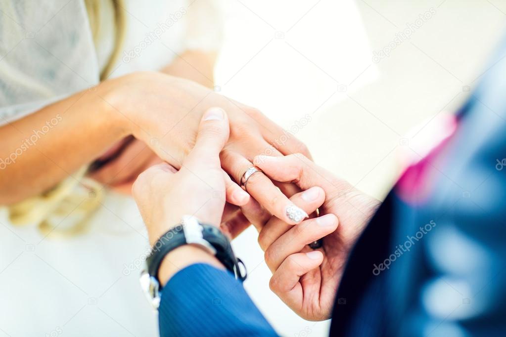 groom placing an engagement ring 